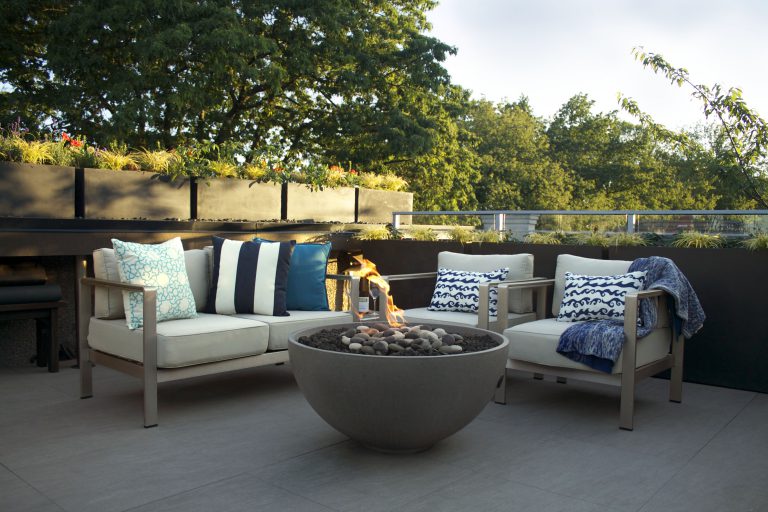 Tall outdoor planters placed along a patio ledge and behind outdoor furniture to create privacy and visual division.