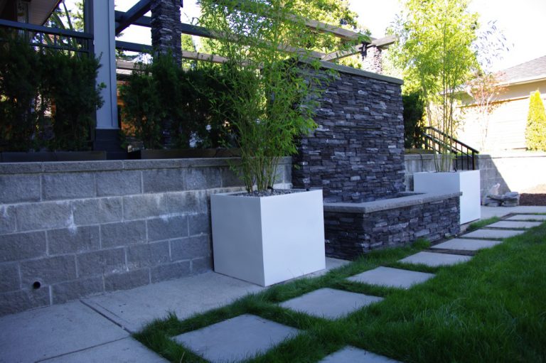 Large white cube planters flanking a residential waterfall feature.